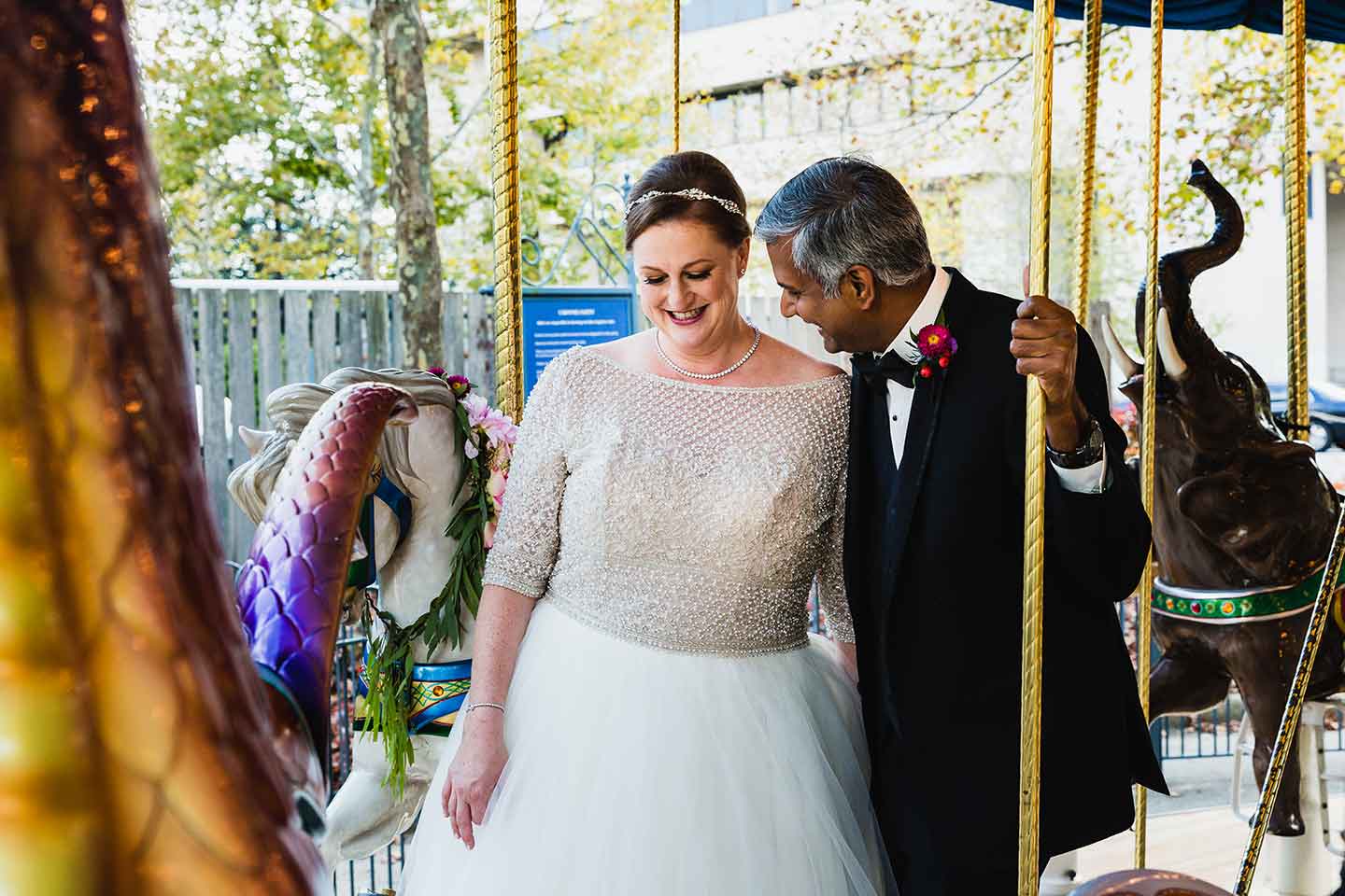 bride and groom laughing together on the merry go round carousel