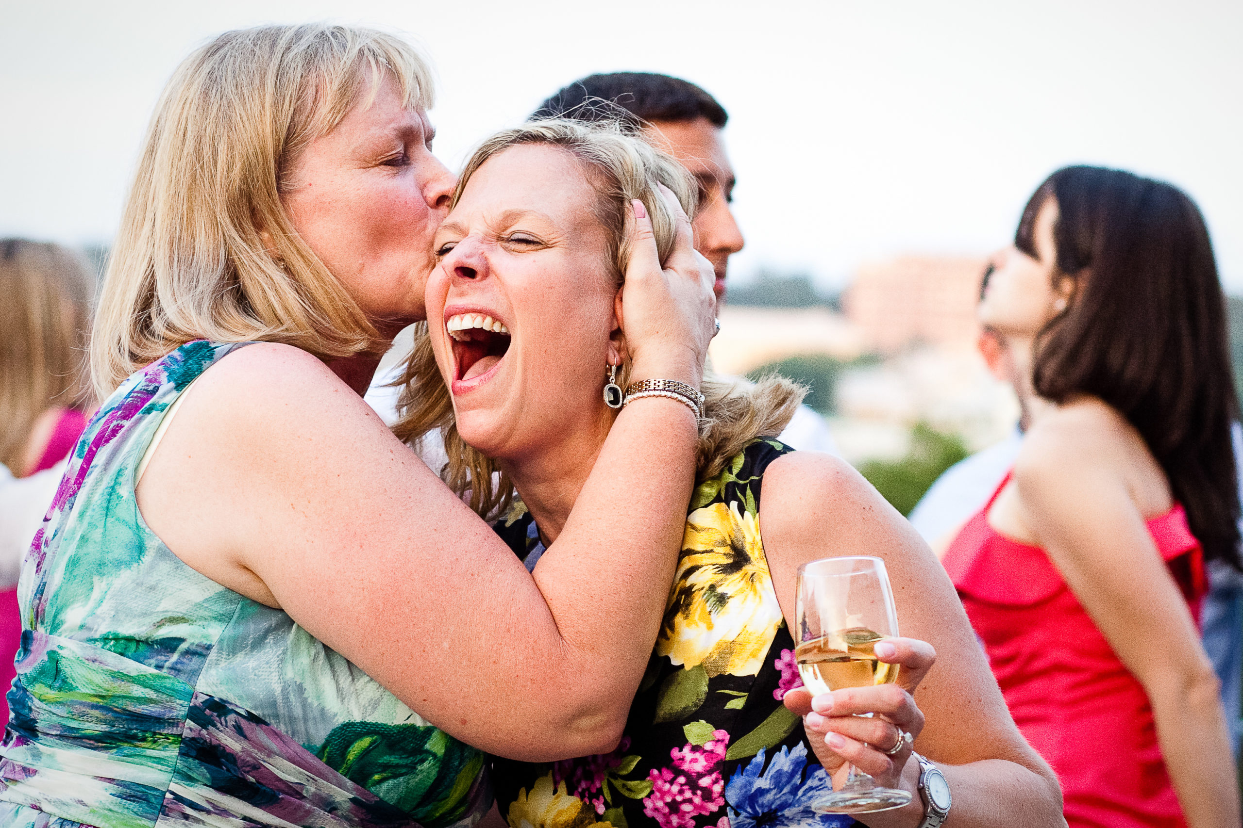 women laughing and kissing on a dance floor while holding wine